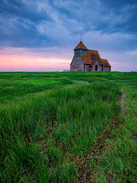 Traditional windmill on field against sky during sunset