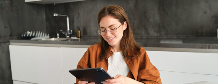 Young woman using digital tablet while sitting on table