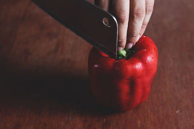 Close-up of hand holding red berries on table