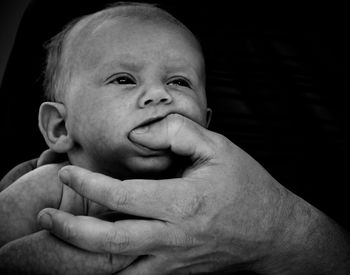 Close-up of cute baby boy biting father thumb