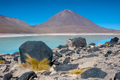 Scenic view of lake and mountains against clear blue sky