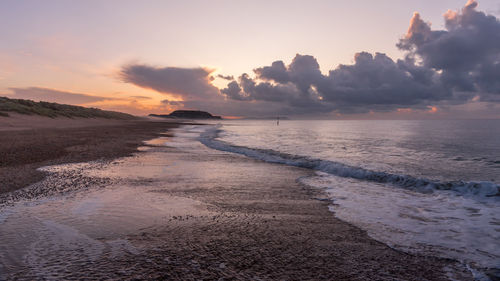 Scenic view of beach against sky during sunset
