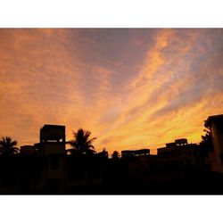 Houses against cloudy sky at sunset