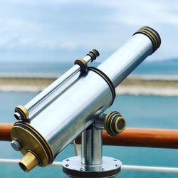 Close-up of coin-operated binoculars by sea against sky