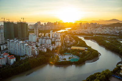 High angle view of river amidst buildings in city during sunset