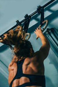 Low angle view of woman holding gymnastic rings 