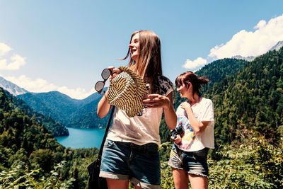 Girls standing on mountain against sky