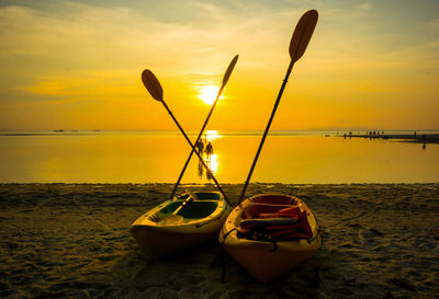 Boat moored on beach against sky during sunset