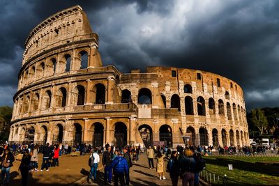 Group of people in front of historical building against cloudy sky