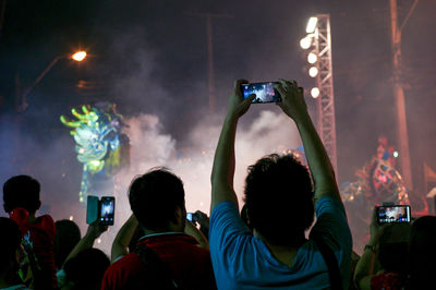 Rear view of people photographing at night