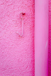 Detail of nail hanging on rose-colored wall in burano