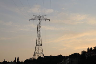 Silhouette electricity pylon and trees against sky at sunset