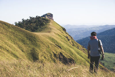 Rear view of woman standing on mountain against clear sky