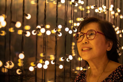 Portrait of smiling woman with illuminated lights at night