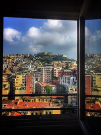 High angle view of buildings against sky seen through glass window