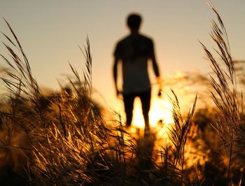 Silhouette man standing on field against sky during sunset