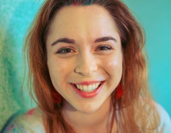 Close-up portrait of smiling young woman against gray background