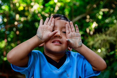 Close-up of boy covering eyes with hands