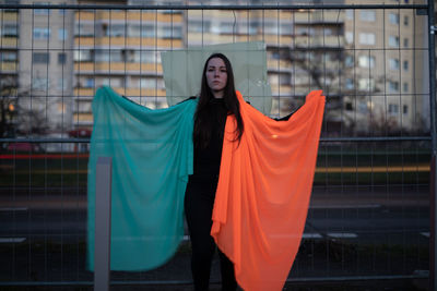 Young woman standing against orange wall