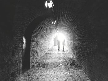 Silhouette friends walking in illuminated tunnel