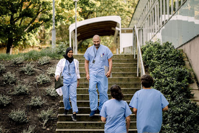 Smiling female and male colleagues with file moving down on staircase