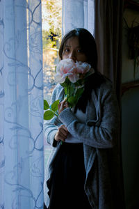 Portrait of woman standing by window