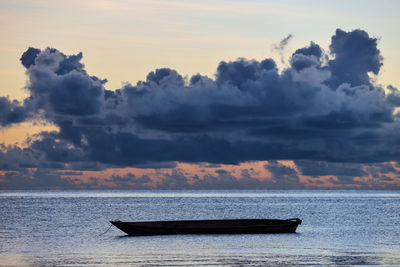 Boat in sea against sky during sunset