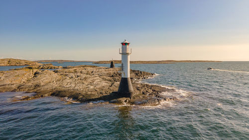 Lighthouse by sea against clear sky