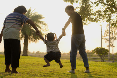 Rear view of family walking on field