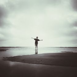 Full length of man standing on beach against sky
