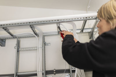 Female technician installing cables in industry