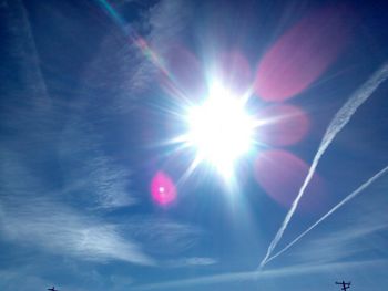 Low angle view of sun shining through clouds