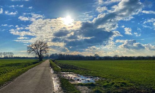 Road amidst field against sky