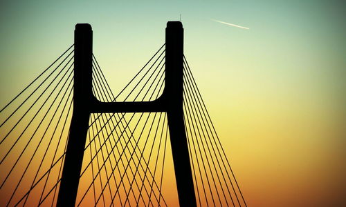 Low angle view of suspension bridge against sky during sunset