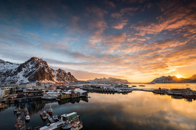 Scenic view of sea by snowcapped mountains against sky during sunset