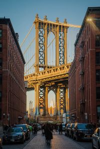 People on street against manhattan bridge in city