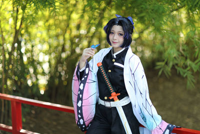 Portrait of young woman standing against trees