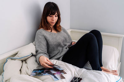 Young woman sitting on bed at home