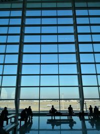 Silhouette people at airport against sky