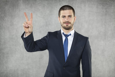 Portrait of young man standing against gray background