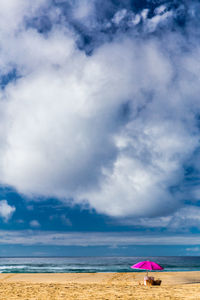 Scenic view of beach against cloudy sky