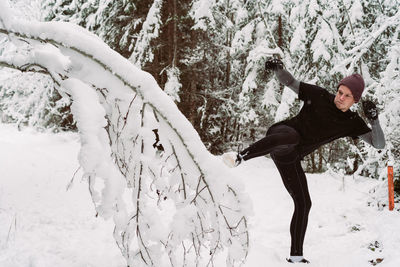 Man kicking snowy tree