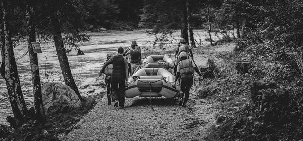 Rear view of people sitting on road amidst trees in forest
