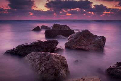 Rocks on sea against sky during sunset