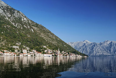 Scenic view of lake and mountains against clear blue sky