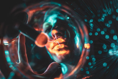 Close-up portrait of woman with illuminated bulb and fiber optic in nightclub