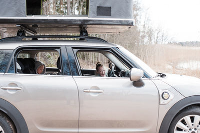 Child sitting in the drivers seat of a car with a roof top tent