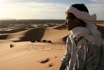 Woman on sand dune in desert against sky