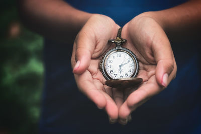 Midsection of person holding pocket watch