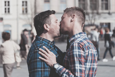 Side view of gay couple kissing on mouth in city